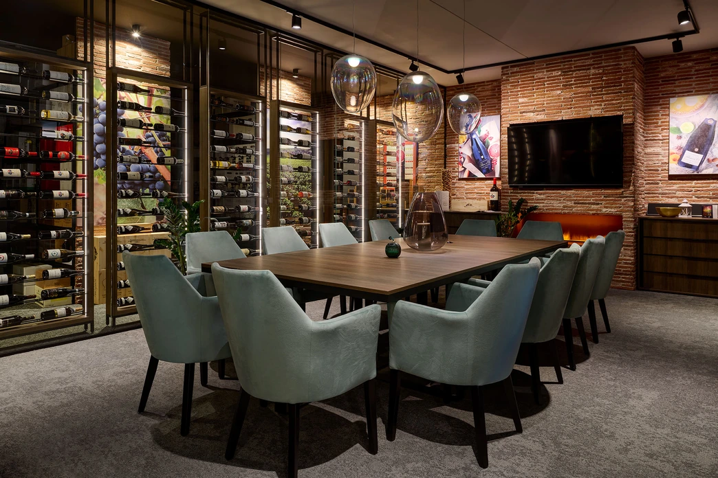 Luxusní jídelna v našem kuchyňském studiu s prosklenou stěnou na víno, dřevěným jídelním stolem, mátově zelenými čalouněnými židlemi, odkrytými cihlovými stěnami, závěsnými světly a připevněnou televizívou stěnou