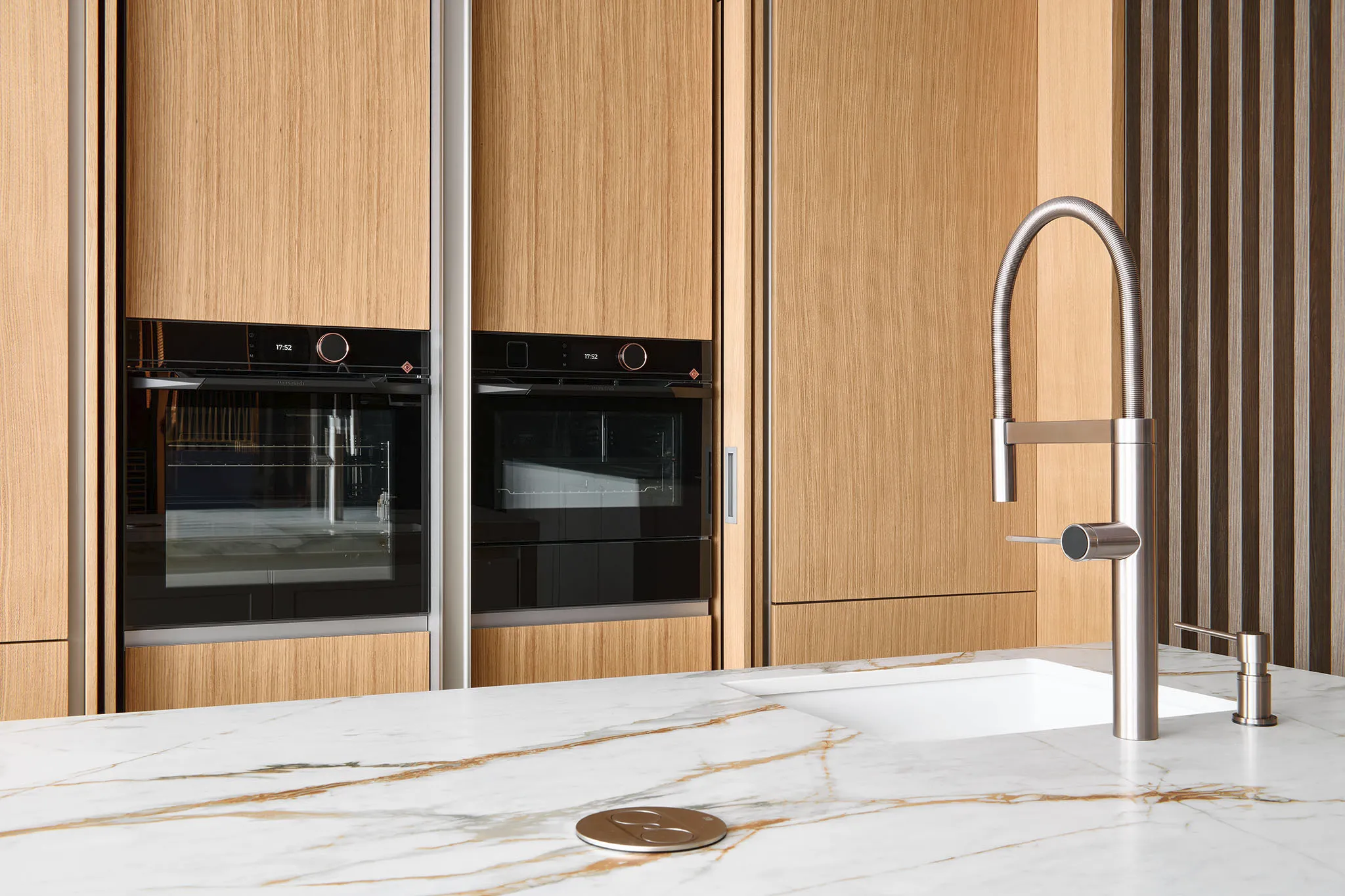 Bílá luxusní elegantní kuchyně s bílým mramorovým ostrůvkem a keramickým dřezem.